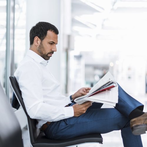 Businessman reading a newspaper in waiting hall